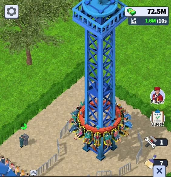 The Drop Tower standing in Theme Park Manager: the blue lattice tower rises above the park path with guests walking below, trees and queue rails framing the plot, seen through the game's elevated diagonal camera